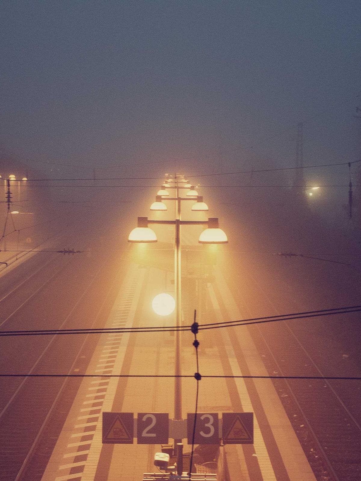 Headlights cutting through dense fog on an empty road